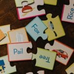 Kolorowe edukacyjne puzzle z wyrazami i obrazkami na drewnianej podłodze