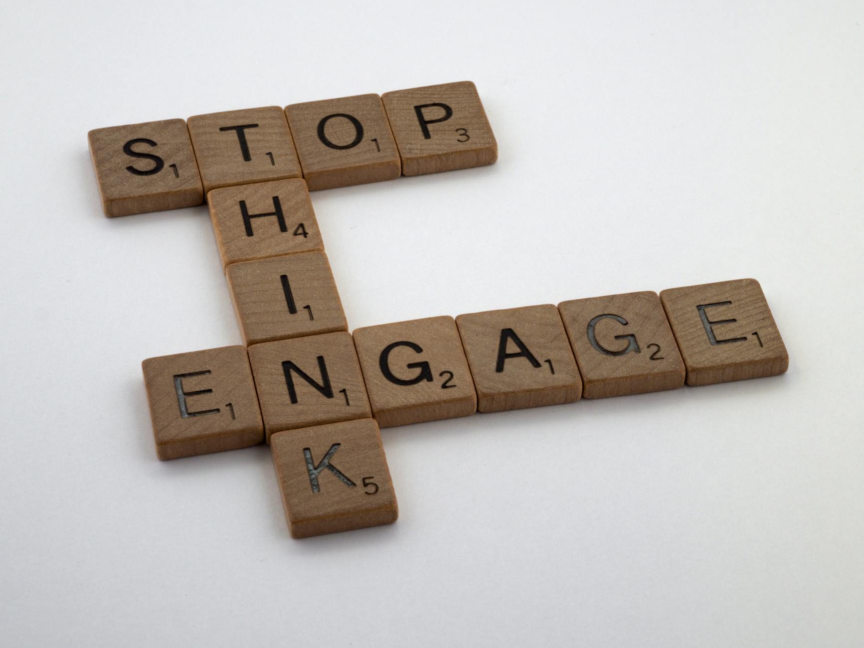 Drewniane płytki Scrabble układające się w napis Stop Think Engage