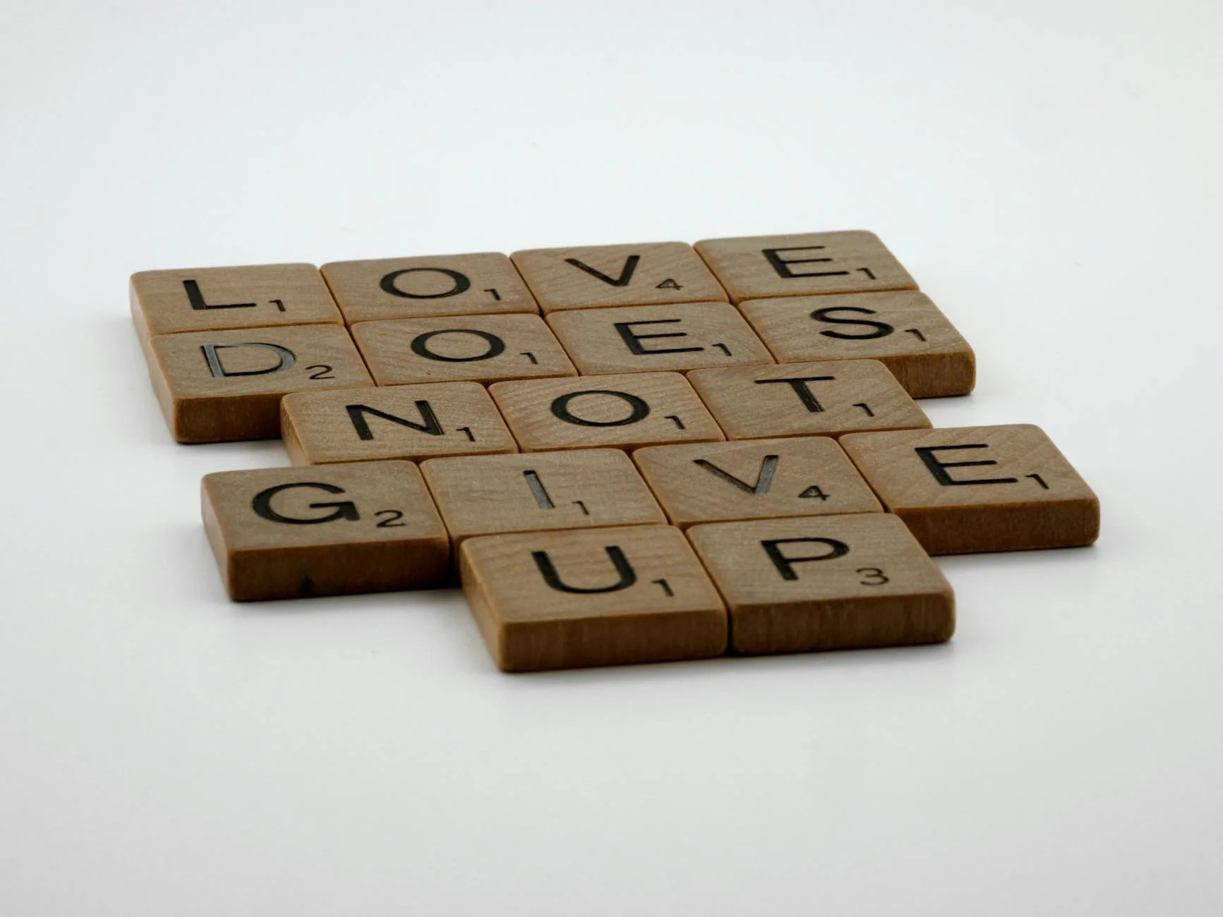 Kafelki Scrabble układające się w hasło Love does not give up