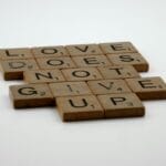 Płytki scrabble z napisem Love does not give up na białym tle