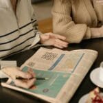 Starsze kobiety przy kawie rozwiązują krzyżówkę w gazecie