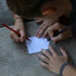 Dłonie rozwiązujące krótką łamigłówkę słowną ołówkiem na kartce na dworze