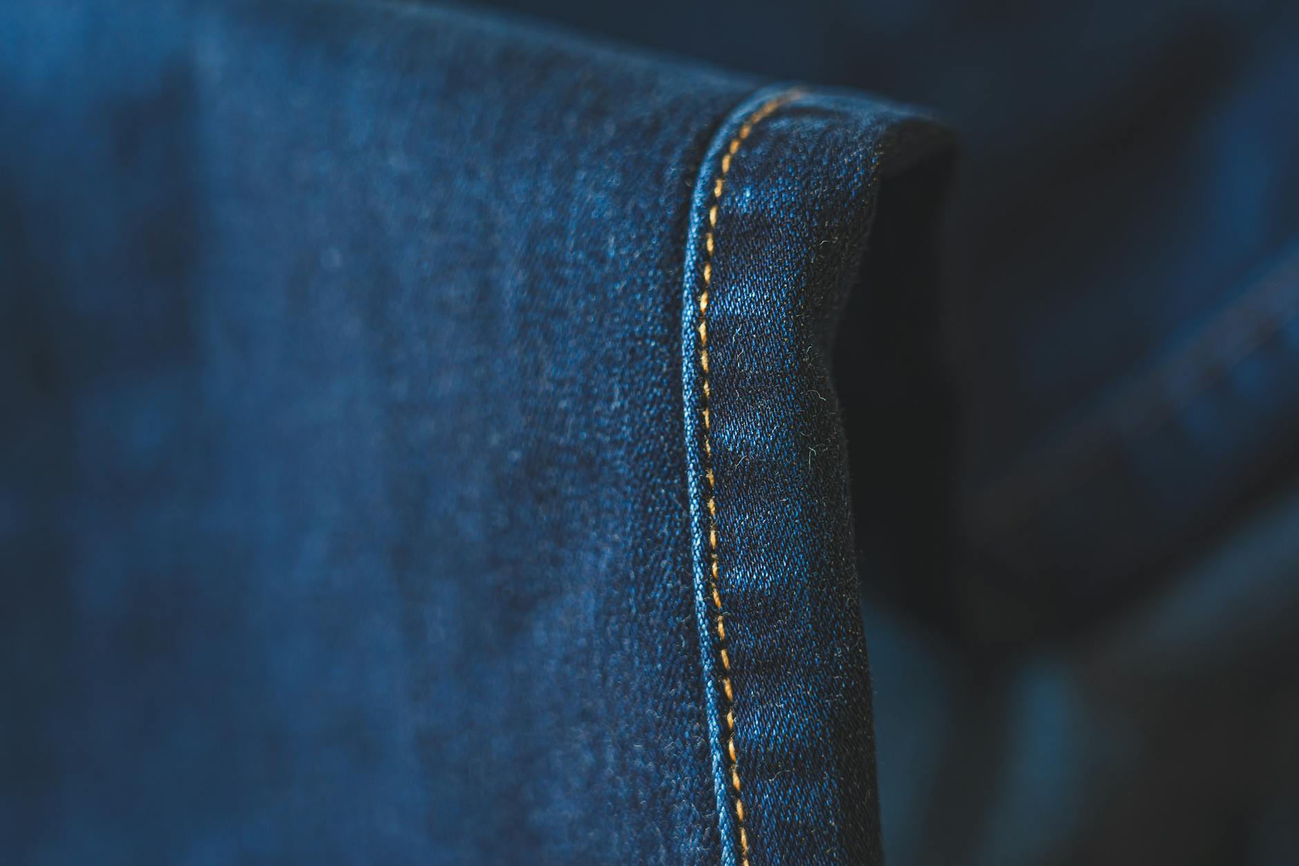 Zbliżenie na niebieski denim z widocznymi ściegami nogawki spodni