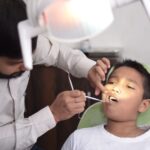 Dentysta sprawdza zęby dziecka w jasnym gabinecie stomatologicznym