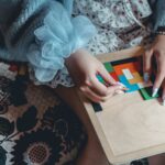 Kobieta w niebieskim swetrze układa kolorową łamigłówkę przy biurku