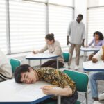 Studenci w sali podczas egzaminu, skupieni na rozwiązywaniu testu