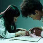 Dwoje dzieci układa puzzle w domu, ćwicząc koncentrację i współpracę